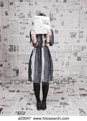 Young woman hiding face behind newspaper in newspapers covered room, studio shot View Large Photo Image Stock Photo - Young woman hiding face behind newspaper in newspapers covered room, studio shot. Fotosearch