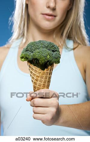 Stock Image - Young woman holding broccoli ice cream. Fotosearch