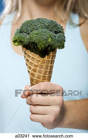 Stock Image - Young woman holding broccoli ice cream. Fotosearch