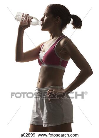 Young woman in sportswear drinking water, studio shot View Large Photo Image Stock Photo - Young woman in sportswear drinking water, studio shot. Fotosearch