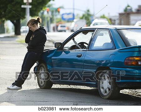 young woman leaning on her car after an accident View Large Photo Image Stock Image - young woman leaning on her car after an accident. Fotosearch