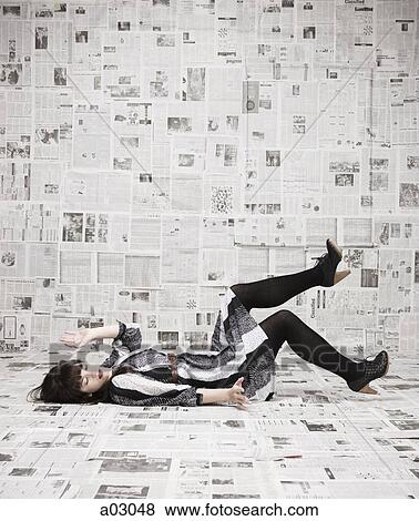 Young woman lying on back in newspapers covered room, studio shot View Large Photo Image Stock Photo - Young woman lying on back in newspapers covered room, studio shot. Fotosearch