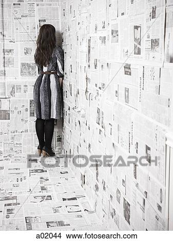 Young woman standing in corner of room covered with newspapers View Large Photo Image Picture - Young woman standing in corner of room covered with newspapers. Fotosearch