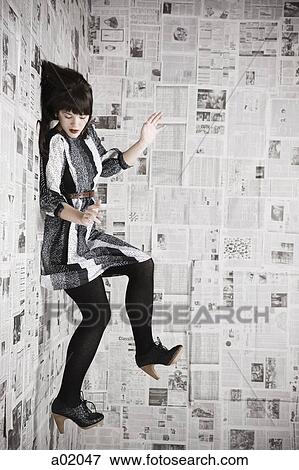 Young woman stuck to wall covered with newspapers, studio shot View Large Photo Image Stock Photo - Young woman stuck to wall covered with newspapers, studio shot. Fotosearch