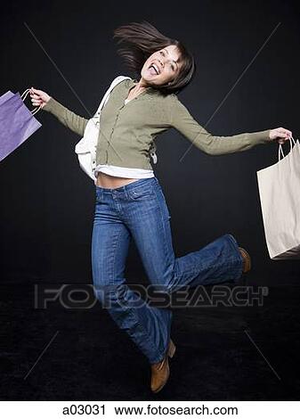 Young woman with shopping bags jumping, studio shot View Large Photo Image Stock Image - Young woman with shopping bags jumping, studio shot. Fotosearch