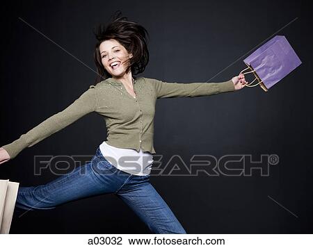 Young woman with shopping bags jumping, studio shot View Large Photo Image Stock Image - Young woman with shopping bags jumping, studio shot. Fotosearch