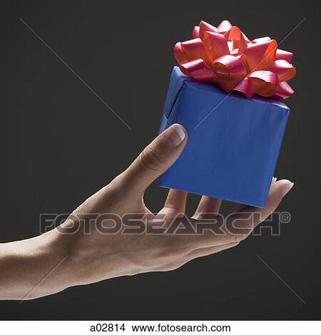 Young woman's hand holding wrapped gift View Large Photo Image Picture - Young woman's hand holding wrapped gift. Fotosearch