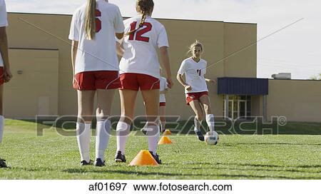 Stock Photo - Athlete with soccer teammates kicking ball in soccer goal on field. Fotosearch