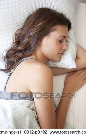 Stock Image - Attractive young woman sleeping in bed. Fotosearch