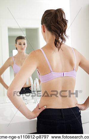Stock Photo - Attractive young woman standing in front of mirror. Fotosearch