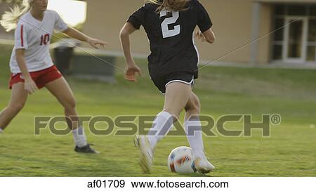 Stock Photo - Blurred view of athlete kicking soccer ball on field. Fotosearch