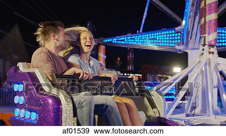 Stock Photo - Blurred view of romantic boyfriend and girlfriend riding ride at amusement park funfair. Fotosearch