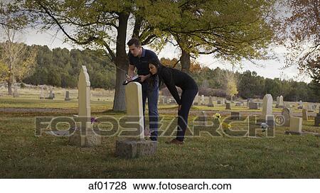 Boyfriend and girlfriend examining grave in lonely cemetery View Large Photo Image Stock Photo - Boyfriend and girlfriend examining grave in lonely cemetery. Fotosearch