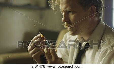 Stock Photograph - Close up of drug addict loading syringe needle for injection. Fotosearch
