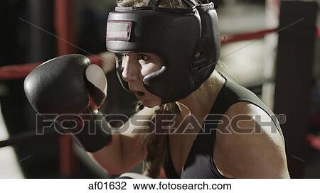 Close up of female boxer in boxing gloves and helmet standing in boxing ring during match View Large Photo Image Stock Image - Close up of female boxer in boxing gloves and helmet standing in boxing ring during match. Fotosearch
