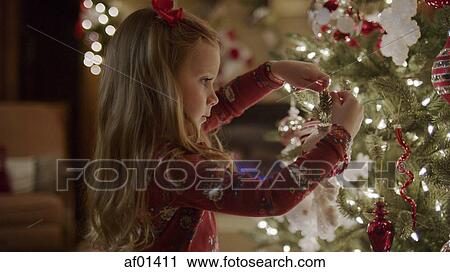 Close up of girl decorating Christmas tree with illuminated lights View Large Photo Image Stock Image - Close up of girl decorating Christmas tree with illuminated lights. Fotosearch