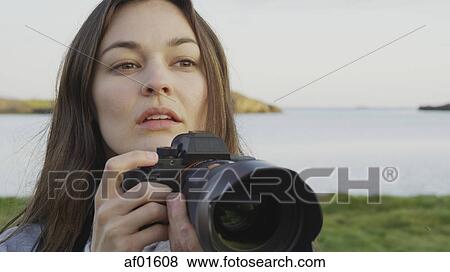 Close up of photographer holding camera in field near lake in remote landscape under blue sky View Large Photo Image Stock Photo - Close up of photographer holding camera in field near lake in remote landscape under blue sky. Fotosearch