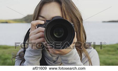 Close up of photographer holding camera in field near lake in remote landscape under blue sky View Large Photo Image Stock Photo - Close up of photographer holding camera in field near lake in remote landscape under blue sky. Fotosearch