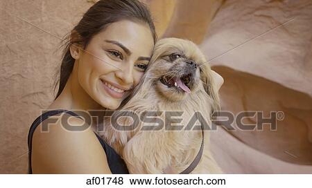 Stock Photo - Close up of portrait of smiling woman holding pet dog. Fotosearch