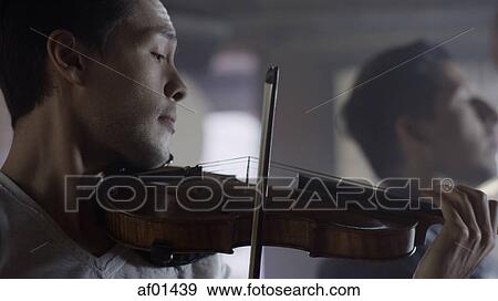 Stock Photo - Close up of serious musician playing violin. Fotosearch