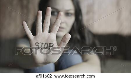 Stock Image - Close up of woman holding out hand with STOP writing on bed. Fotosearch