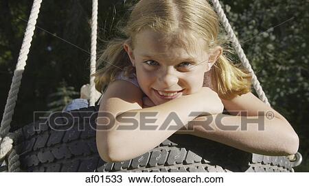Close up portrait of smiling playful girl sitting on tire swing View Large Photo Image Stock Image - Close up portrait of smiling playful girl sitting on tire swing. Fotosearch