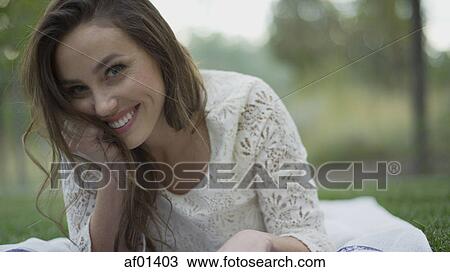 Close up portrait of smiling woman laying in grass View Large Photo Image Stock Image - Close up portrait of smiling woman laying in grass. Fotosearch