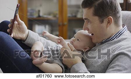 Close up profile of smiling father taking smartphone selfie with baby daughter on sofa View Large Photo Image Stock Image - Close up profile of smiling father taking smartphone selfie with baby daughter on sofa. Fotosearch