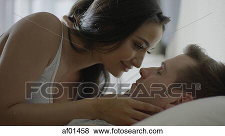 Stock Photo - Close up profile of smiling happy couple laying on bed. Fotosearch