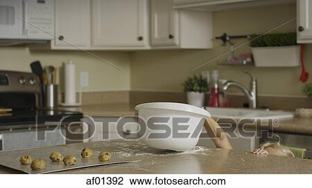 Curious girl reaching for bowl of cookie dough on kitchen counter View Large Photo Image Stock Image - Curious girl reaching for bowl of cookie dough on kitchen counter. Fotosearch