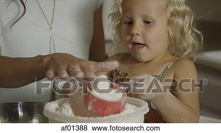 Curious girl scooping flour and learning to bake in kitchen View Large Photo Image Stock Photo - Curious girl scooping flour and learning to bake in kitchen. Fotosearch