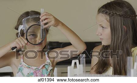 Curious students examining test tube with magnifying glass in science laboratory experiment View Large Photo Image Picture - Curious students examining test tube with magnifying glass in science laboratory experiment. Fotosearch