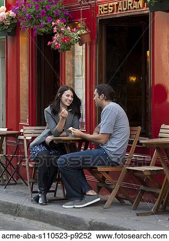 Stock Image - France, Couple sitting in sidewalk cafe. Fotosearch