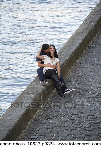 Picture - France, Paris, Seine River, Young couple relaxing on promenade. Fotosearch