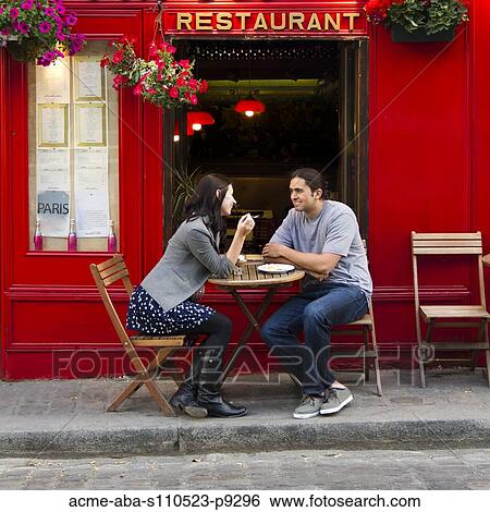 Stock Photograph - France, Paris, Young couple sitting in sidewalk cafe. Fotosearch