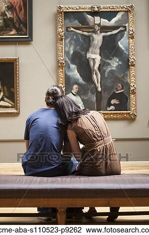 Stock Image - France, Paris, Young couple watching paintings in Louvre Museum. Fotosearch