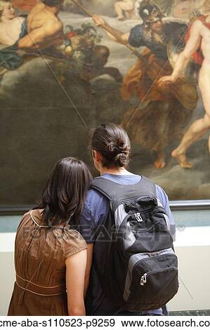 Stock Photo - France, Paris, Young couple watching paintings in Louvre Museum. Fotosearch