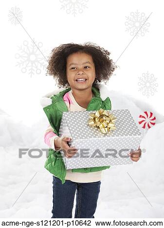 Stock Image - Girl (4-5) holding christmas gift. Fotosearch