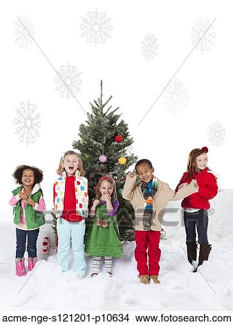 Group of kids (18-23months, 4-5, 6-7) standing next to christmas tree View Large Photo Image Picture - Group of kids (18-23months, 4-5, 6-7) standing next to christmas tree. Fotosearch