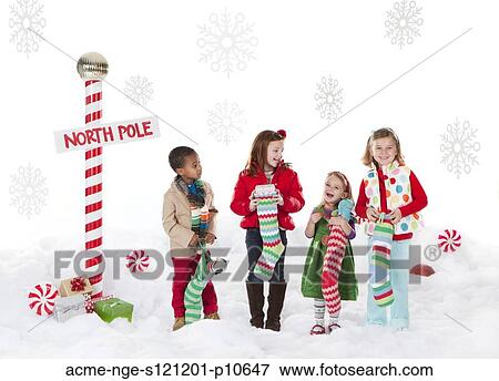 Stock Photo - Group of kids (18-23months, 4-5, 6-7) standing next to North Pole sign. Fotosearch