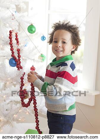 Happy young boy decorating Christmas tree View Large Photo Image Stock Photo - Happy young boy decorating Christmas tree. Fotosearch