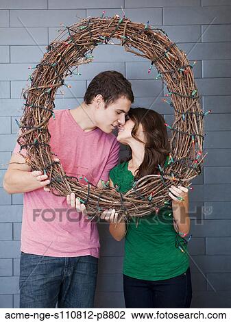 Stock Image - Happy young couple posing with wicker wreath. Fotosearch
