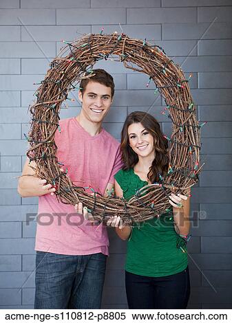 Stock Photography - Happy young couple posing with wicker wreath. Fotosearch
