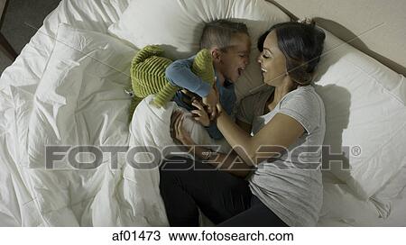 High angle profile view of mother tickling playful son in bed View Large Photo Image Stock Image - High angle profile view of mother tickling playful son in bed. Fotosearch