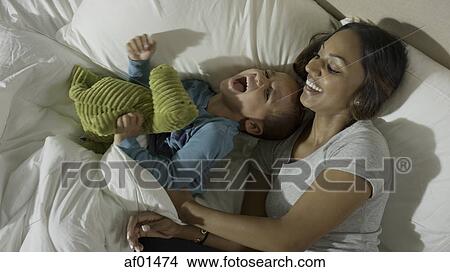 High angle view mother tickling playful son in bed View Large Photo Image Picture - High angle view mother tickling playful son in bed. Fotosearch