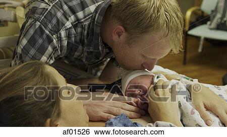 Stock Photograph - High angle view of new mother and father admiring newborn baby in hospital. Fotosearch