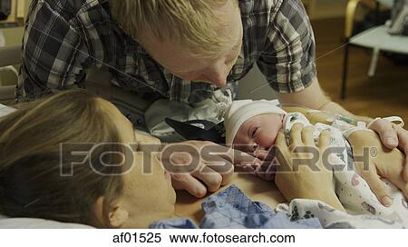 Stock Photography - High angle view of new mother and father admiring newborn baby in hospital. Fotosearch