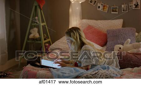 High angle view of teenage girl using digital tablet in bed View Large Photo Image Stock Photo - High angle view of teenage girl using digital tablet in bed. Fotosearch
