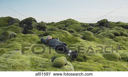 High angle view of woman laying in mossy field in remote rocky landscape under clear blue sky View Large Photo Image Stock Photo - High angle view of woman laying in mossy field in remote rocky landscape under clear blue sky. Fotosearch