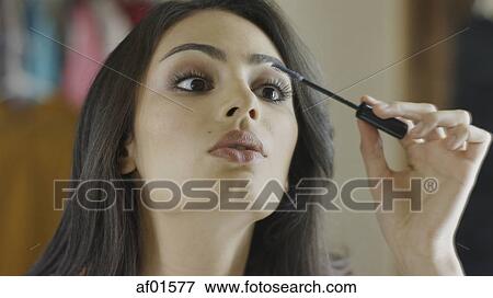 Low angle close up of concentrating woman applying mascara make-up View Large Photo Image Stock Photo - Low angle close up of concentrating woman applying mascara make-up. Fotosearch
